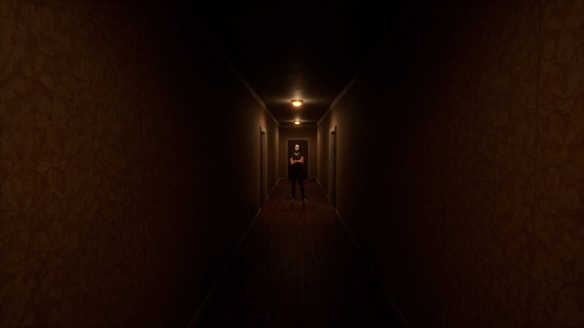 A man wearing a white mask stands with his arms crossed at the end of a hallway